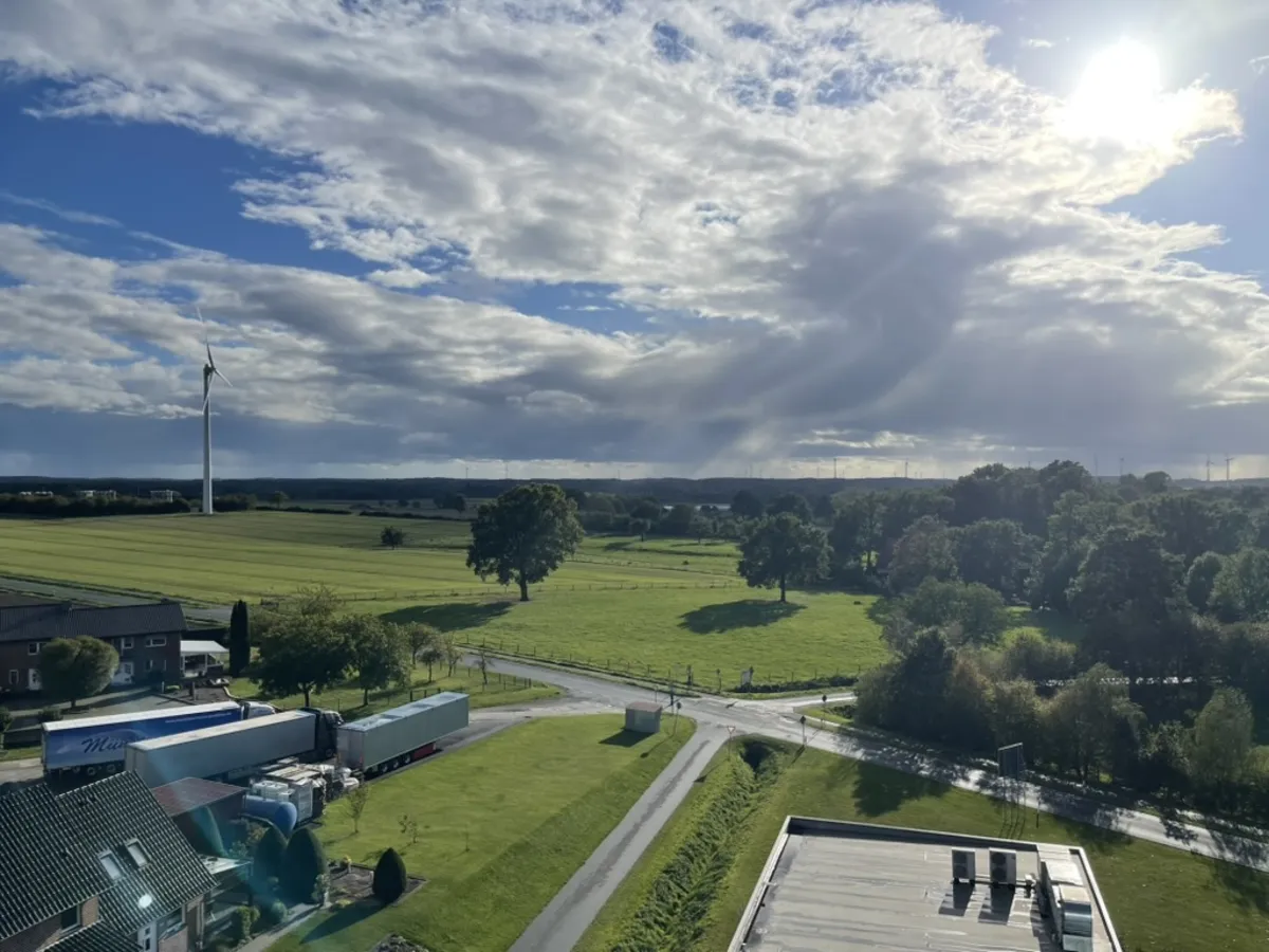 Blick vom Campus über Felder und Windräder bei Schöppingen, die Sonne bricht durch die Wolken