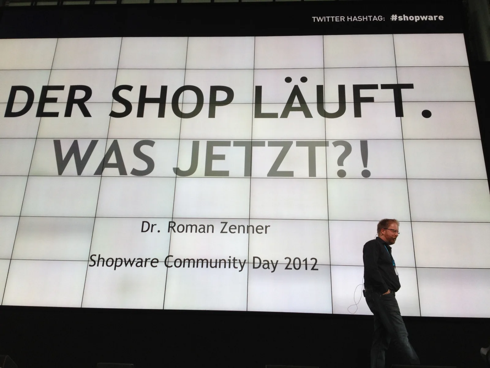 Bühnenfolie mit dem Vortragstitel Der Shop läuft. Was jetzt?! von Dr. Roman Zenner