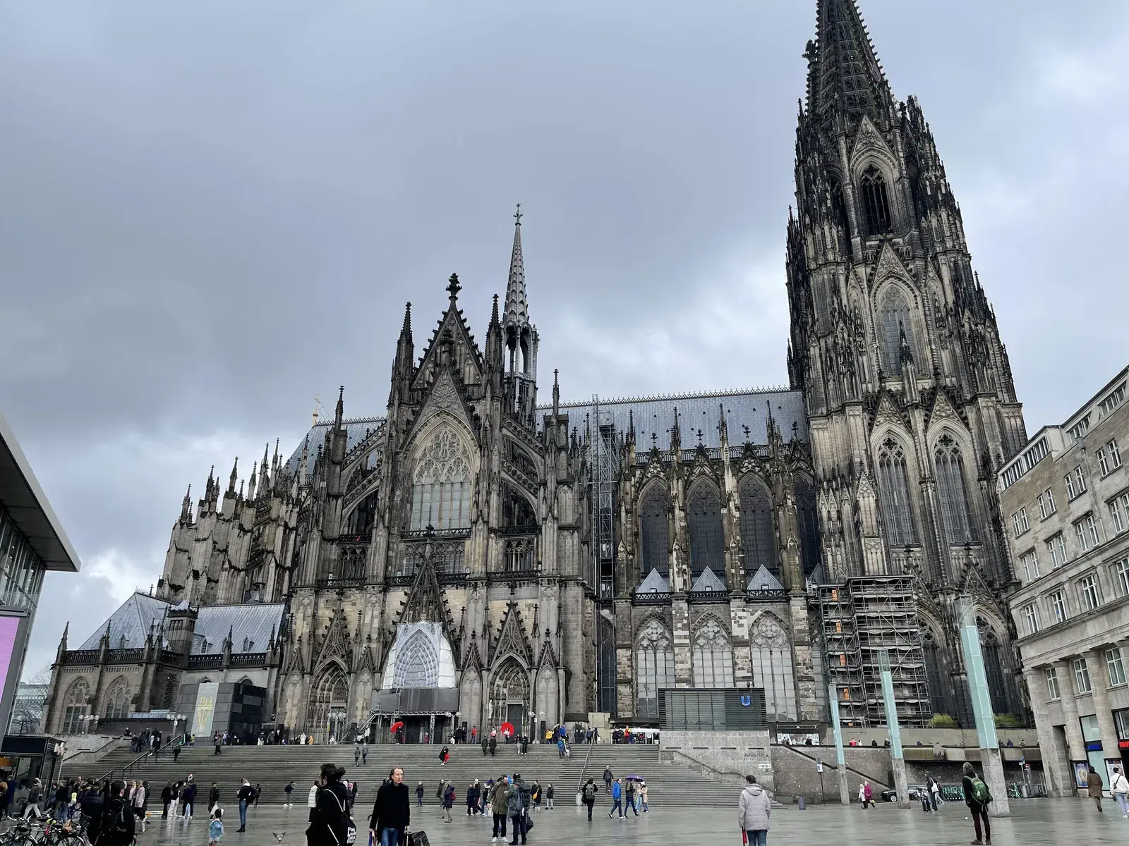 Der Kölner Dom von der Domplatte aus, davor Passanten auf dem Vorplatz