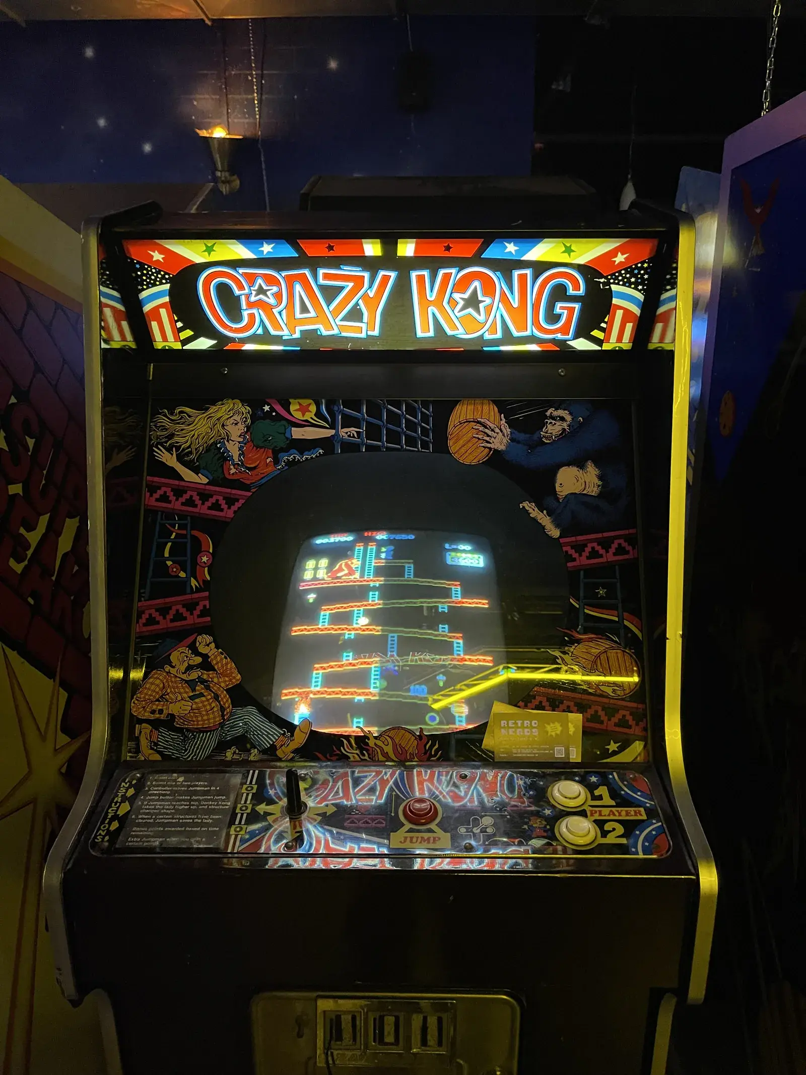 Arcade-Automat Crazy Kong mit beleuchtetem Seitendekor und laufendem Spiel auf der Bildröhre