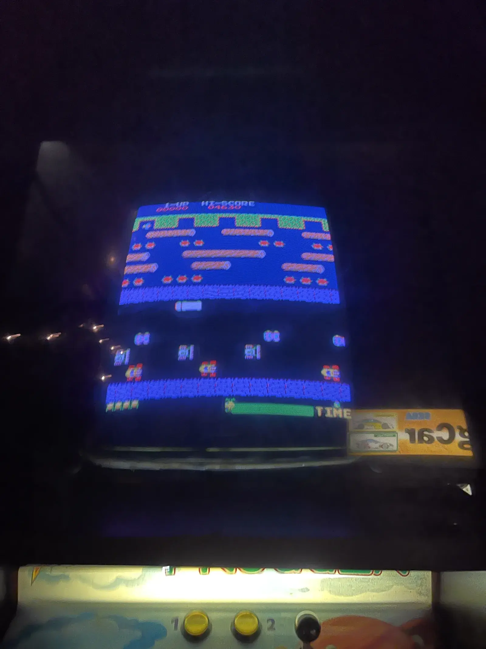 Frogger-Automat im Halbdunkel, auf dem Bildschirm die Straßenszene des Spiels