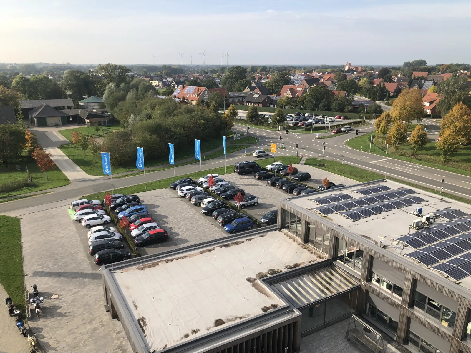 Blick vom Shopware-Gebäude über den Parkplatz mit Shopware-Fahnen auf Schöppingen, am Horizont Windräder